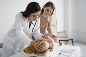 Médico pediatra examinando a un bebé con una madre sonriente observando