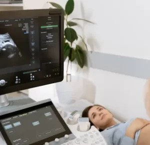 Mujer realizándose una ecografía con monitor mostrando la imagen